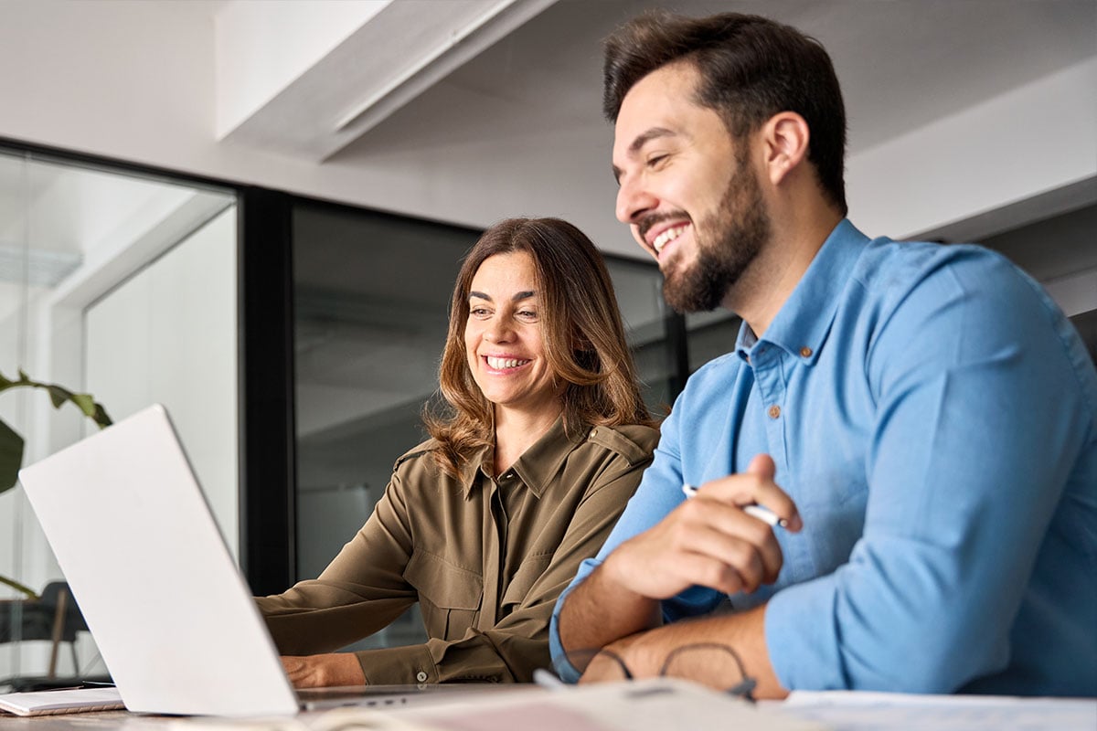 smiling-coworkers-collaborating-on-laptop