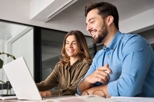smiling-coworkers-collaborating-on-laptop